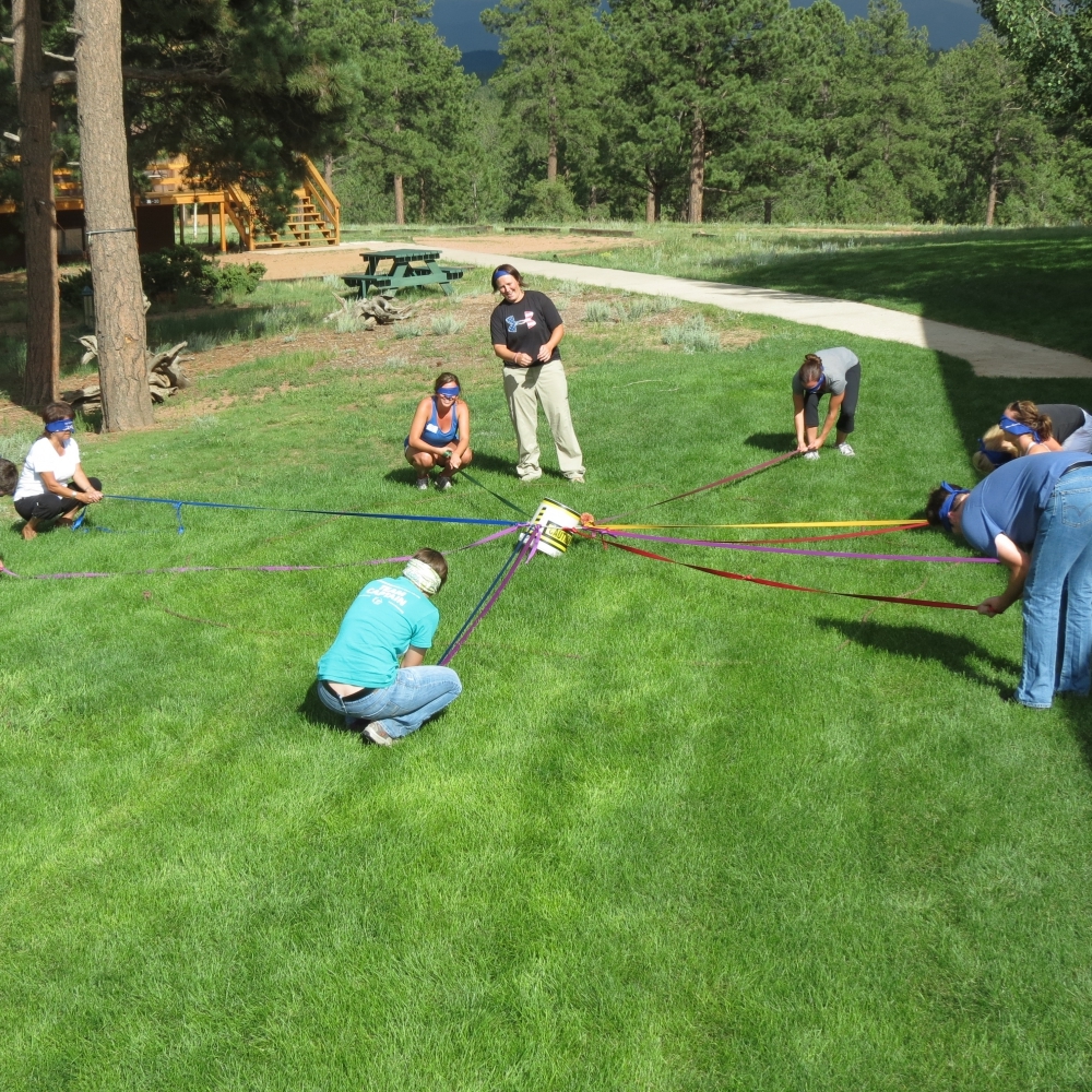 A team working through challenges on The Nature Place lawn